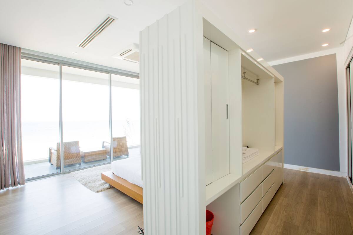 Een moderne hotelkamer met een grote schuifglazen deur naar een balkon, een inbouwkleerkast en een houten vloer.