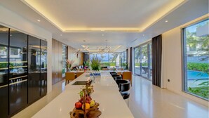 Un espace repas moderne avec une longue table, des chaises et un centre de table composé de fruits.