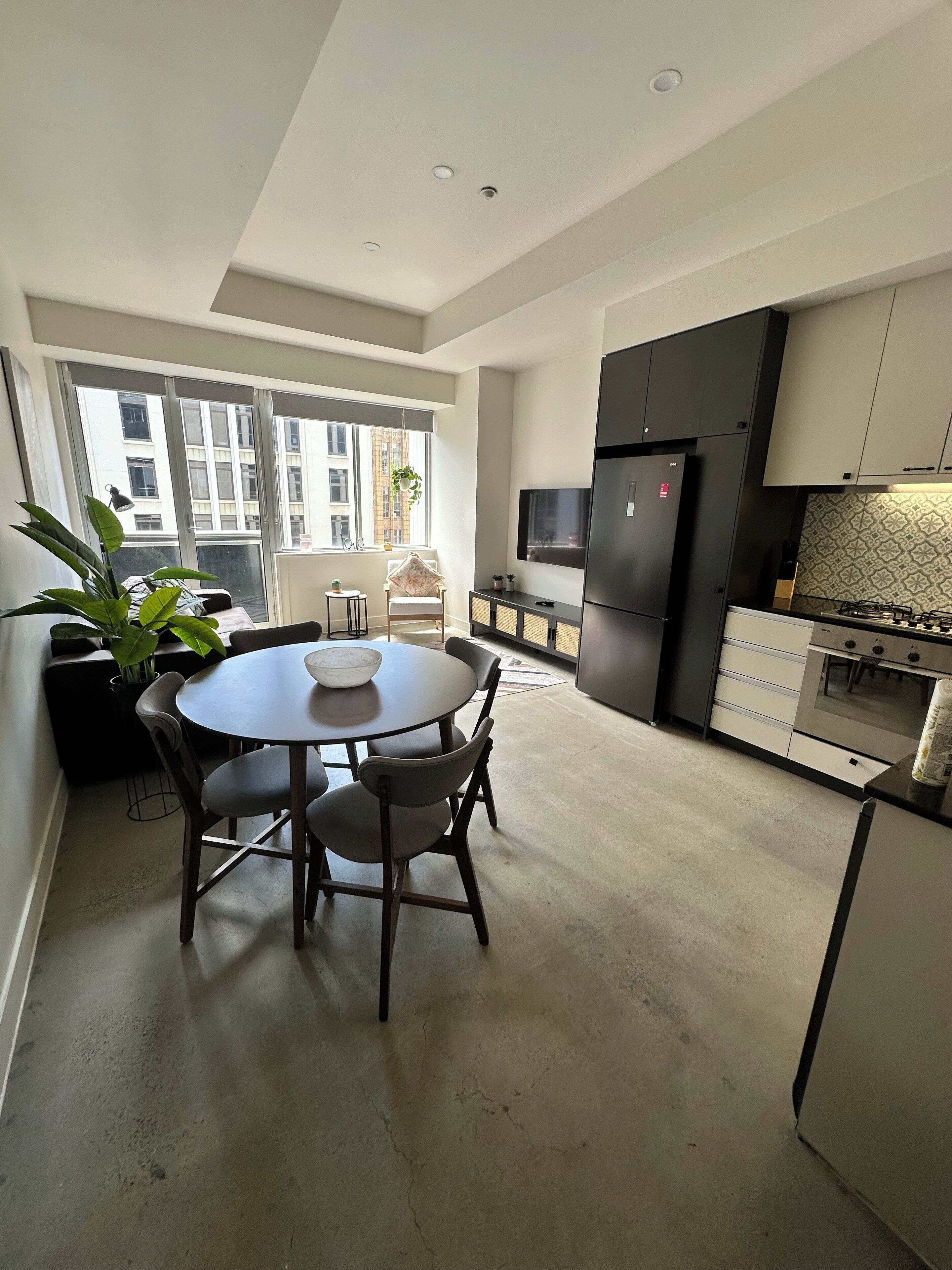 Een moderne keuken met een eethoek, grote ramen en uitzicht op de stad.