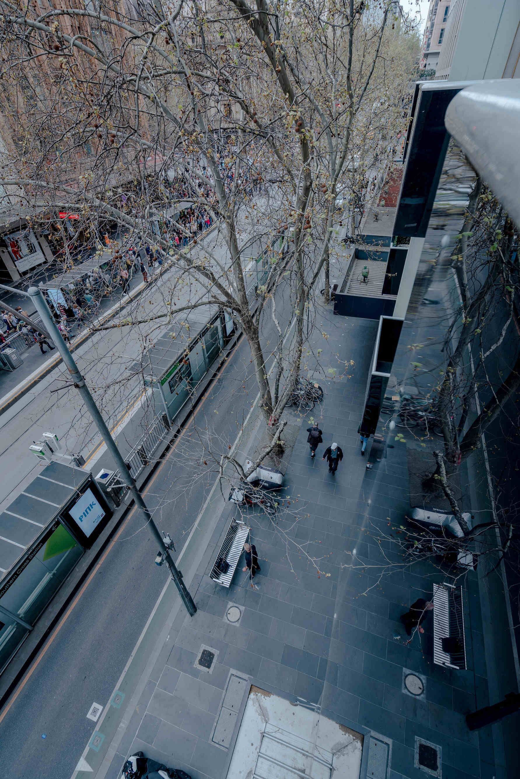 Vue aérienne d’une rue de la ville, avec un tramway, des piétons et des immeubles.