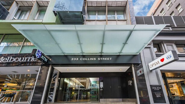 The entrance to a building with a sign reading "233 Collins Street" and an "ATM" sign. - Absolute Collins Apartments (Melbourne)