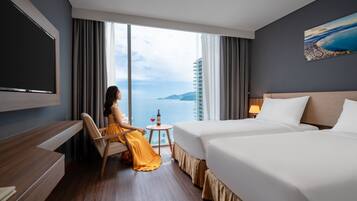 A hotel room with a large window, a bed, a desk, and a chair.