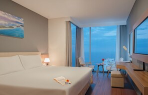 Ein Hotelzimmer mit einem großen Bett, einem Schreibtisch mit Stuhl, einem kleinen Tisch und einem Fernseher.