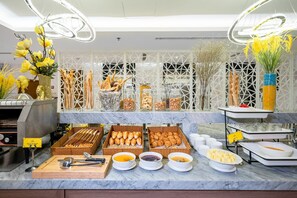 Ein Buffet mit verschiedenen Speisen, darunter Brot, Gebäck und Soßen.