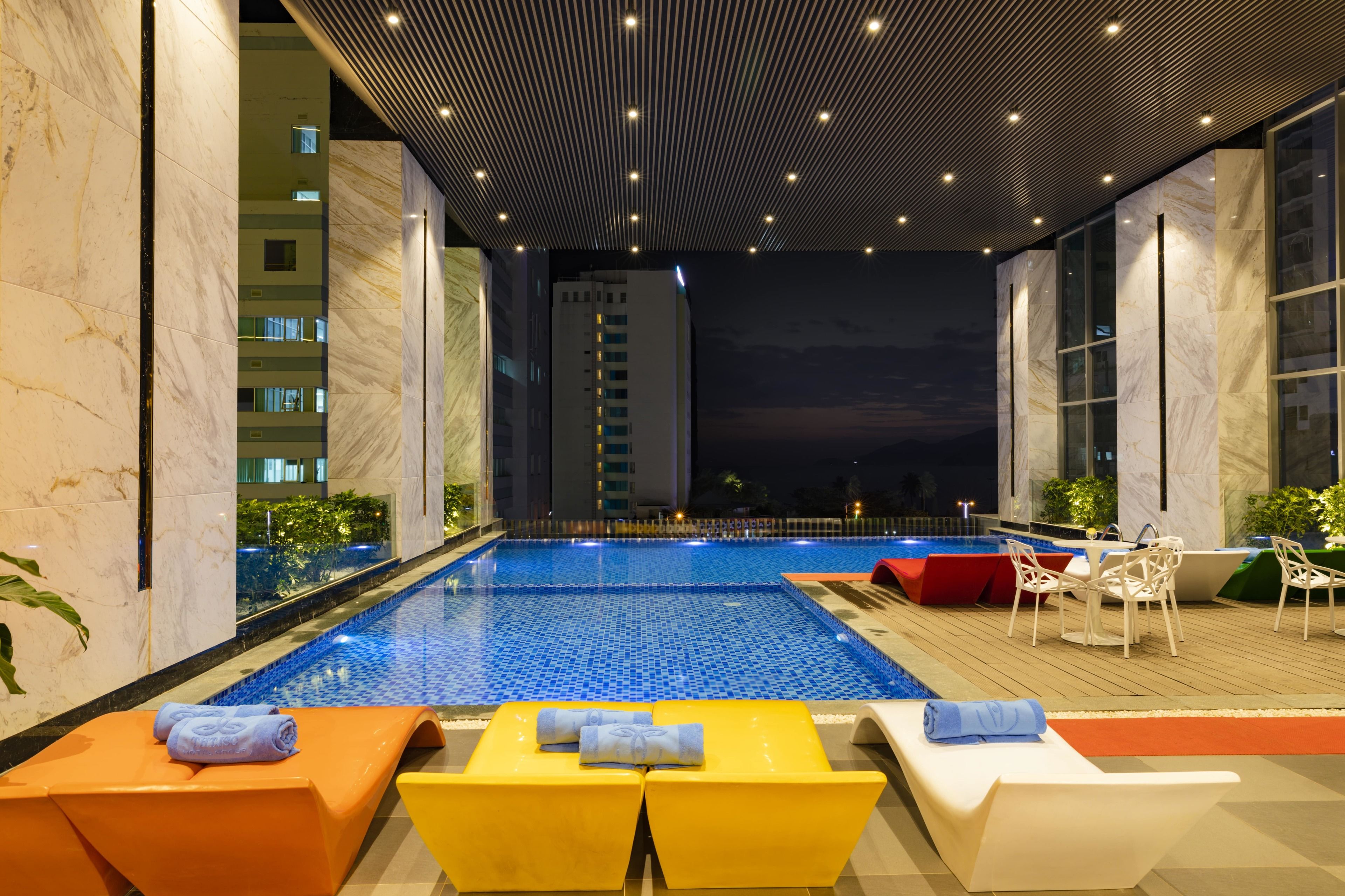 An indoor swimming pool with a view of a tall building at night.