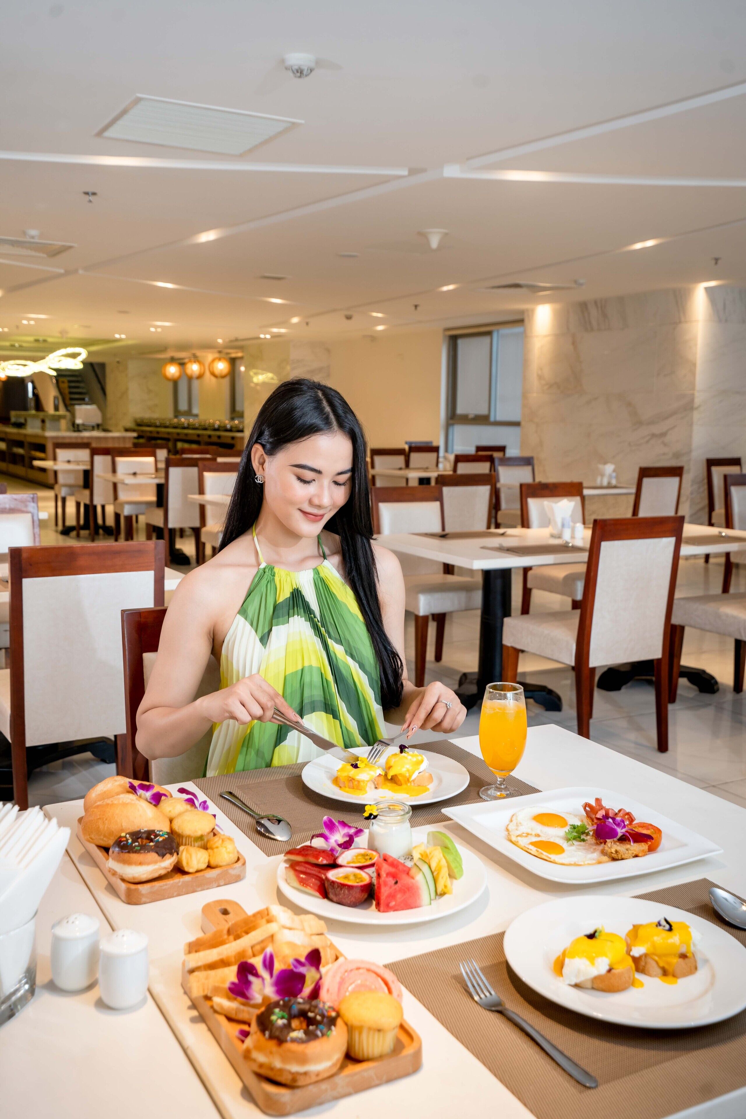 Un espace repas comprenant plusieurs tables, des chaises et une variété de plats pour le petit-déjeuner.