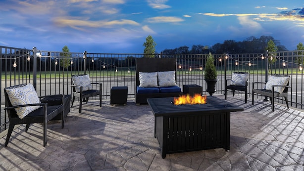 An outdoor patio area with a fire feature, seating arrangements, and string lights. - Garner Hotel Clarksville Northeast by IHG (Clarksville)
