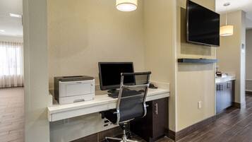 Une chambre d’hôtel équipée d’un bureau, d’un ordinateur, d’une imprimante et d’un téléviseur à écran plat fixé au mur.