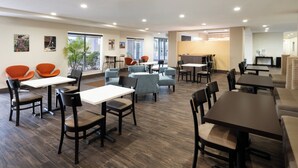 A spacious indoor area with multiple seating arrangements, including tables and chairs, and large windows allowing natural light. - Garner Hotel Clarksville Northeast by IHG (Clarksville)