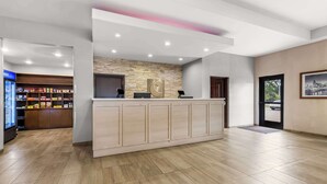 A reception area with a wooden reception desk, a stone accent wall, and a vending machine in the background. - Comfort Suites Columbia I-65 (Columbia)