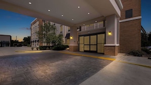 A hotel entrance with a paved driveway, a brick building facade, and a glass door entrance. - Comfort Suites Columbia I-65 (Columbia)