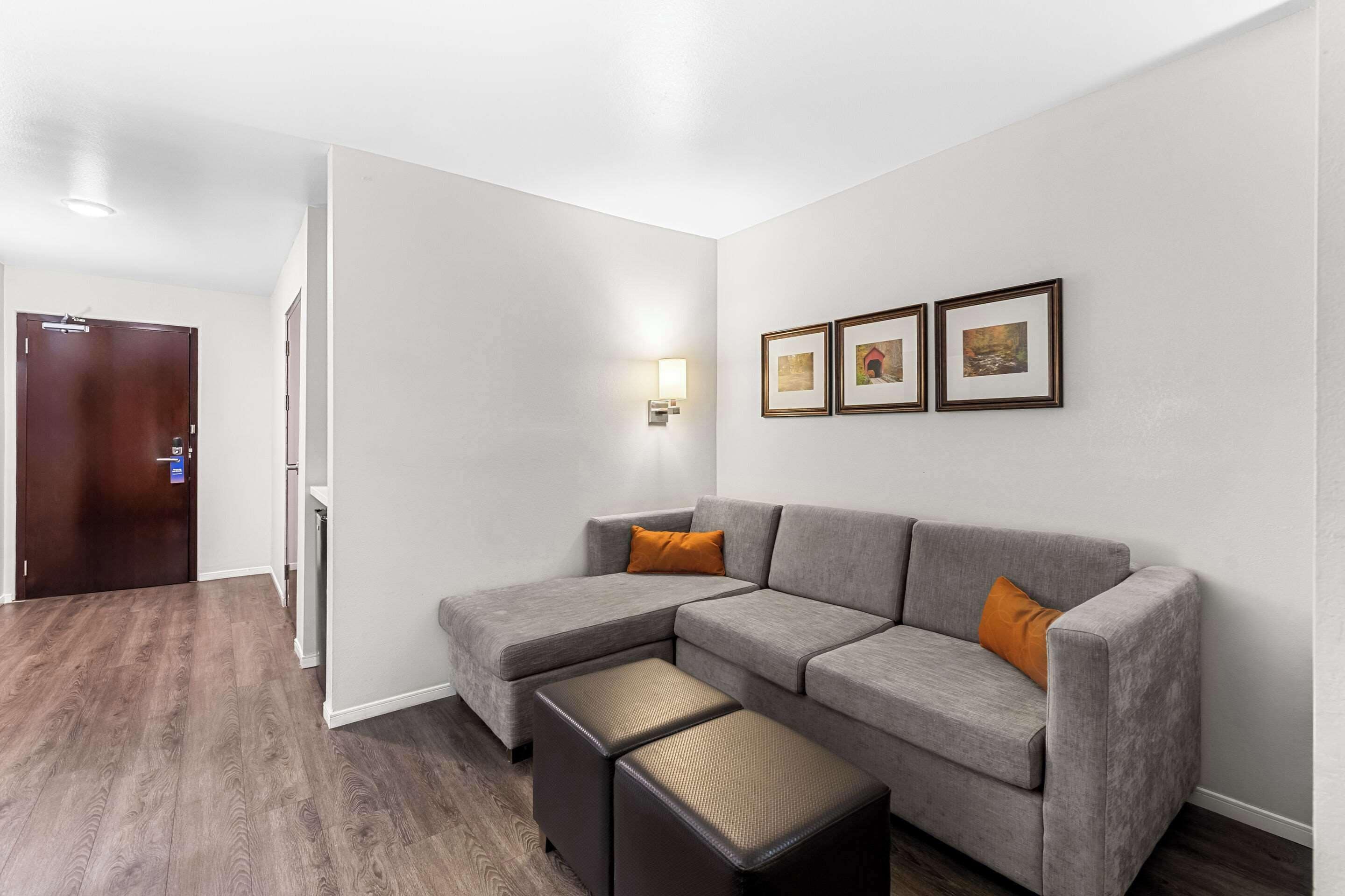 A modern living room with a sectional sofa, a small ottoman, and a wall-mounted light fixture.