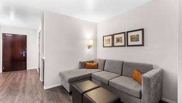A modern living room with a sectional sofa, a small ottoman, and a wall-mounted light fixture.