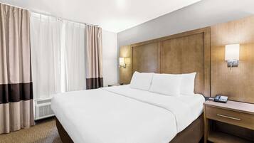 Una camera d'albergo con un letto grande, un comodino con una lampada e un telefono fissato alla parete.