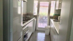 A compact kitchen with a refrigerator, stove, sink, and a window with blinds. - Castlereagh 7 Middleton Beach Albany (Middleton Beach)