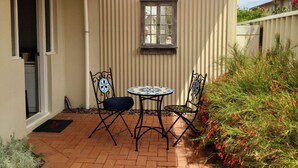A patio with a table and two chairs, a window, and a door leading to a room. - Castlereagh 7 Middleton Beach Albany (Middleton Beach)