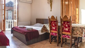 Una camera da letto con un letto, un'armadio in legno, un lampadario e vista su un edificio dall'ampia finestra.