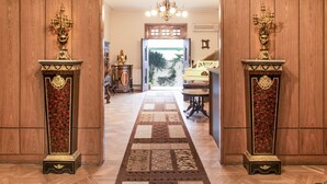 Un corridoio con una moquette decorata, rivestimenti in legno e due elaborati candelabri su ciascun lato.