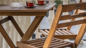 Un tavolo di legno con due tazze e un bicchiere su un balcone che si affaccia su edifici.