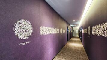 A hallway with purple walls, decorative panels, and a carpeted floor.