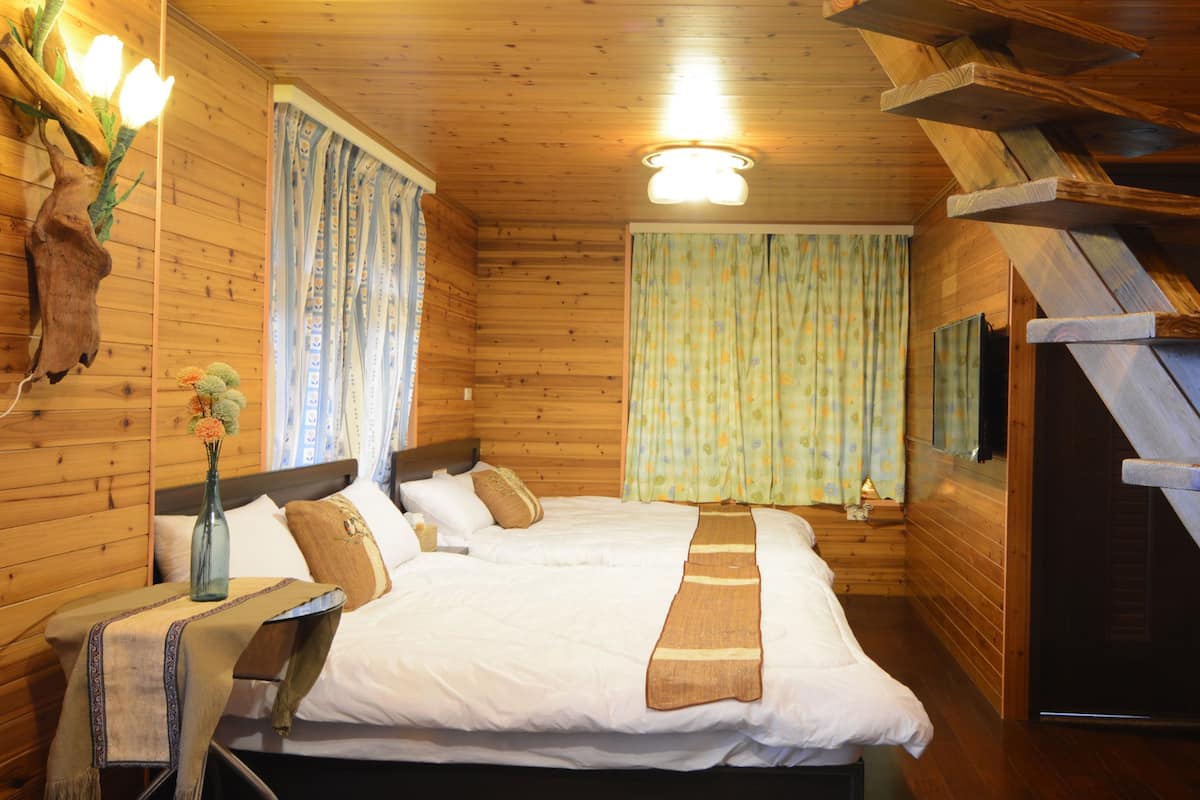Una habitación tipo cabaña de madera con una cama, cortinas, un trofeo de caza y una escalera.