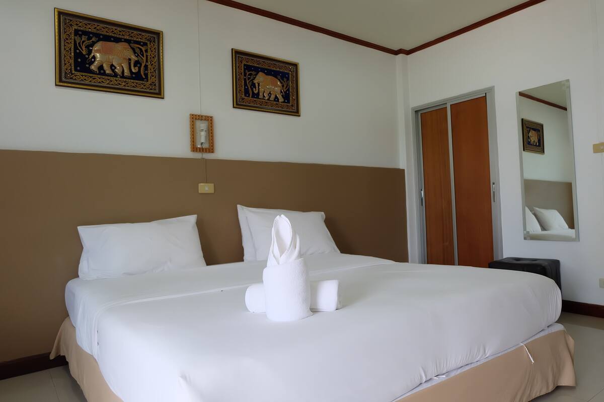 Una cama bien tendida con sábanas blancas, un cabecero y dos cuadros en la pared.