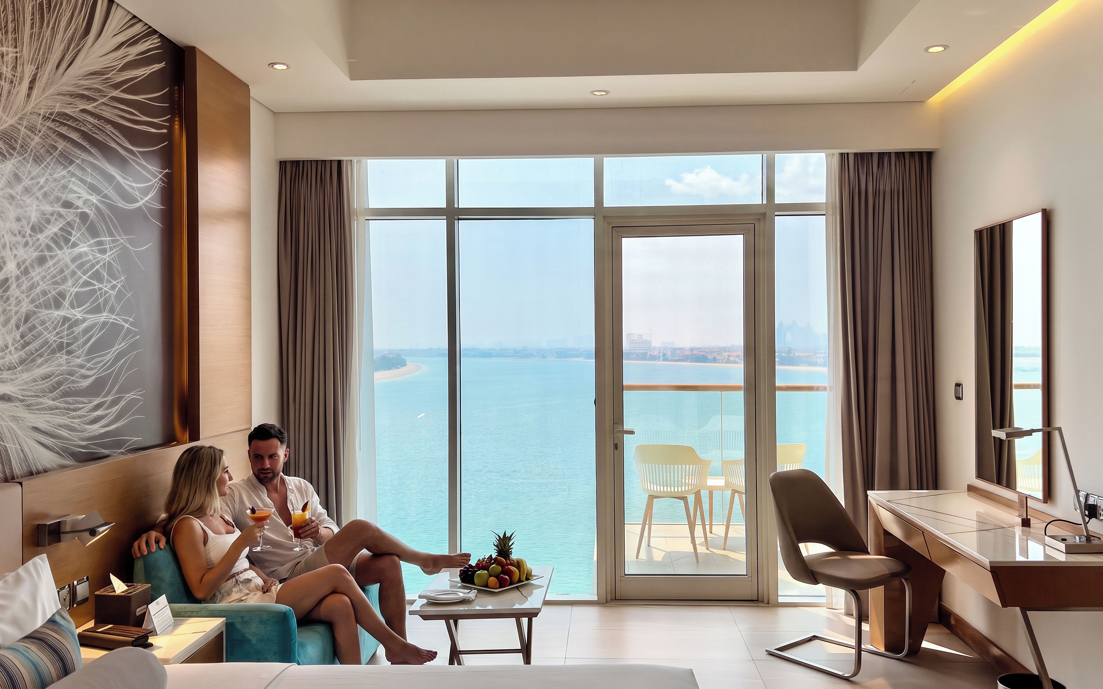 Una habitación de hotel con un ventanal grande, una cama, un escritorio y una mesa de comedor con un frutero.