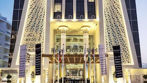 Das Royal Central Hotel mit moderner Fassade, großen Fenstern und einladendem Eingang mit Flaggen und beleuchteten Säulen.