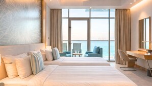 Una habitación de hotel moderna con dos camas, un escritorio y vista al mar.