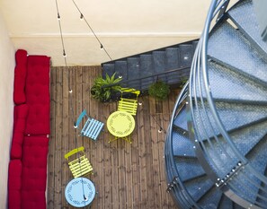 A wooden deck with outdoor furniture, a hanging chair, and a spiral staircase. - Georges Hostel & Café (Sète)