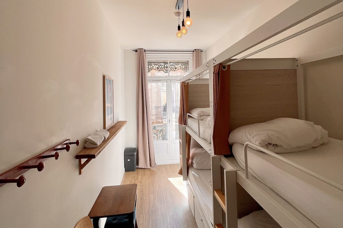 A dormitory room with bunk beds, a desk, and a chair.