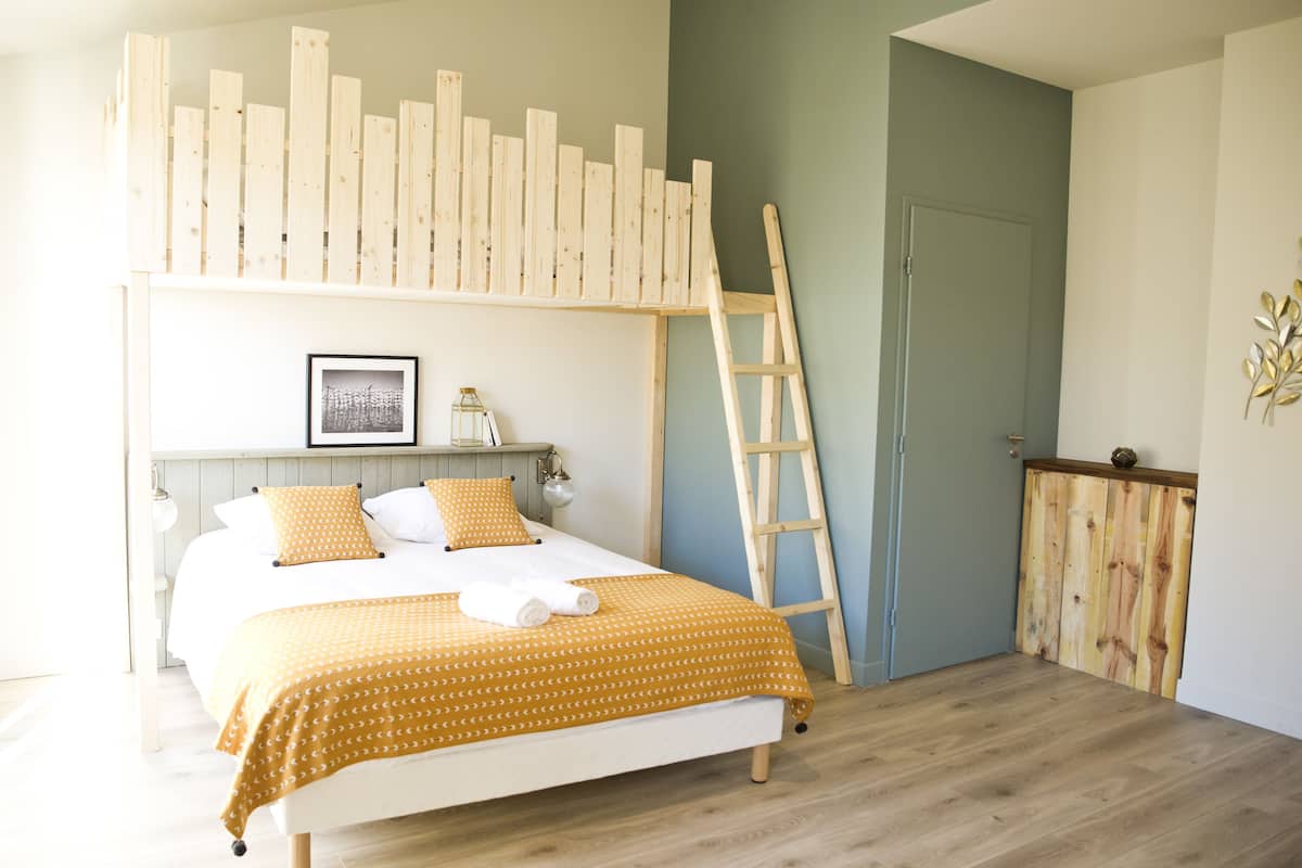 A bedroom with a bed, wooden ladder, and a door.