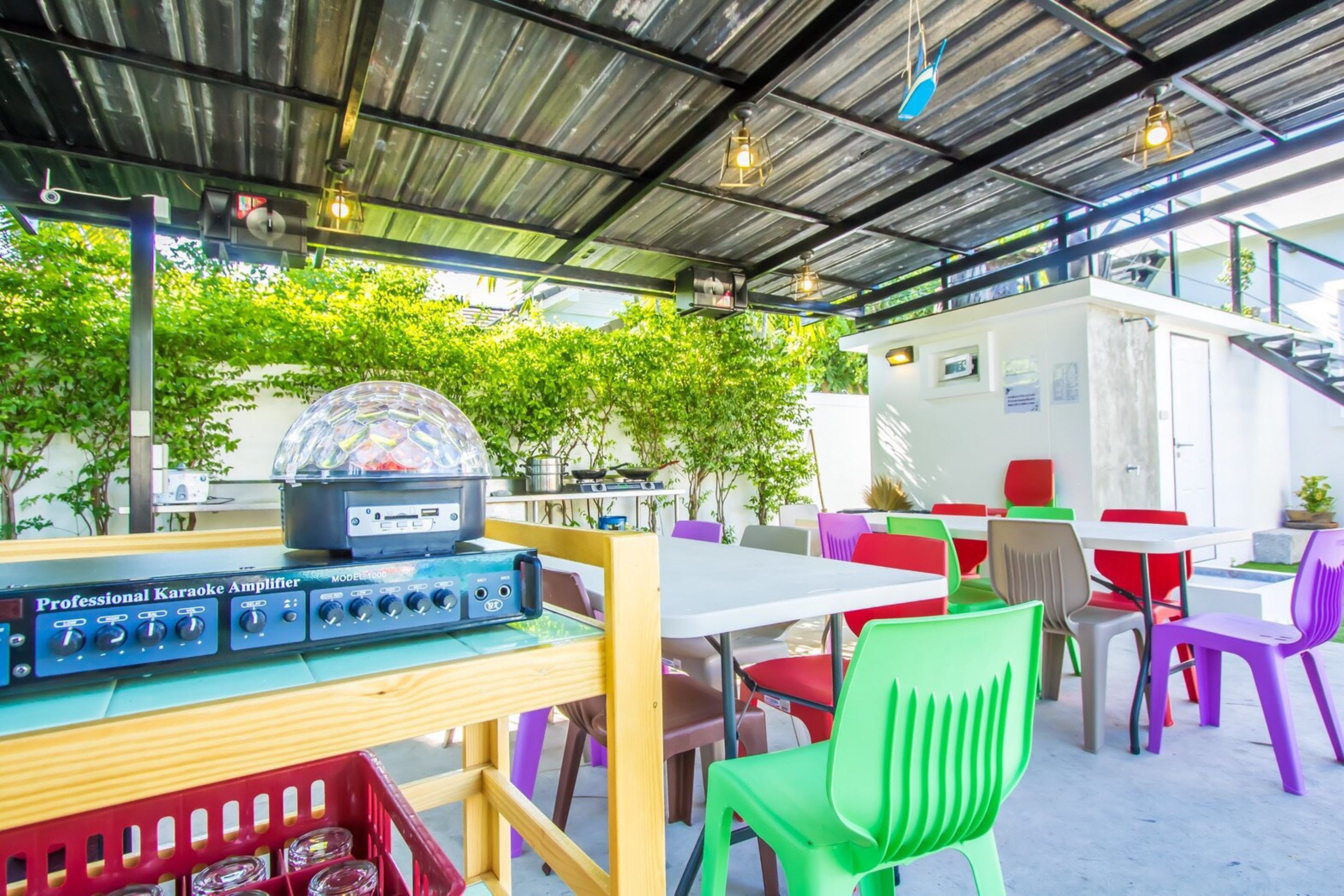 Een terras met kleurrijke stoelen en een karaoke-versterker op een tafel.