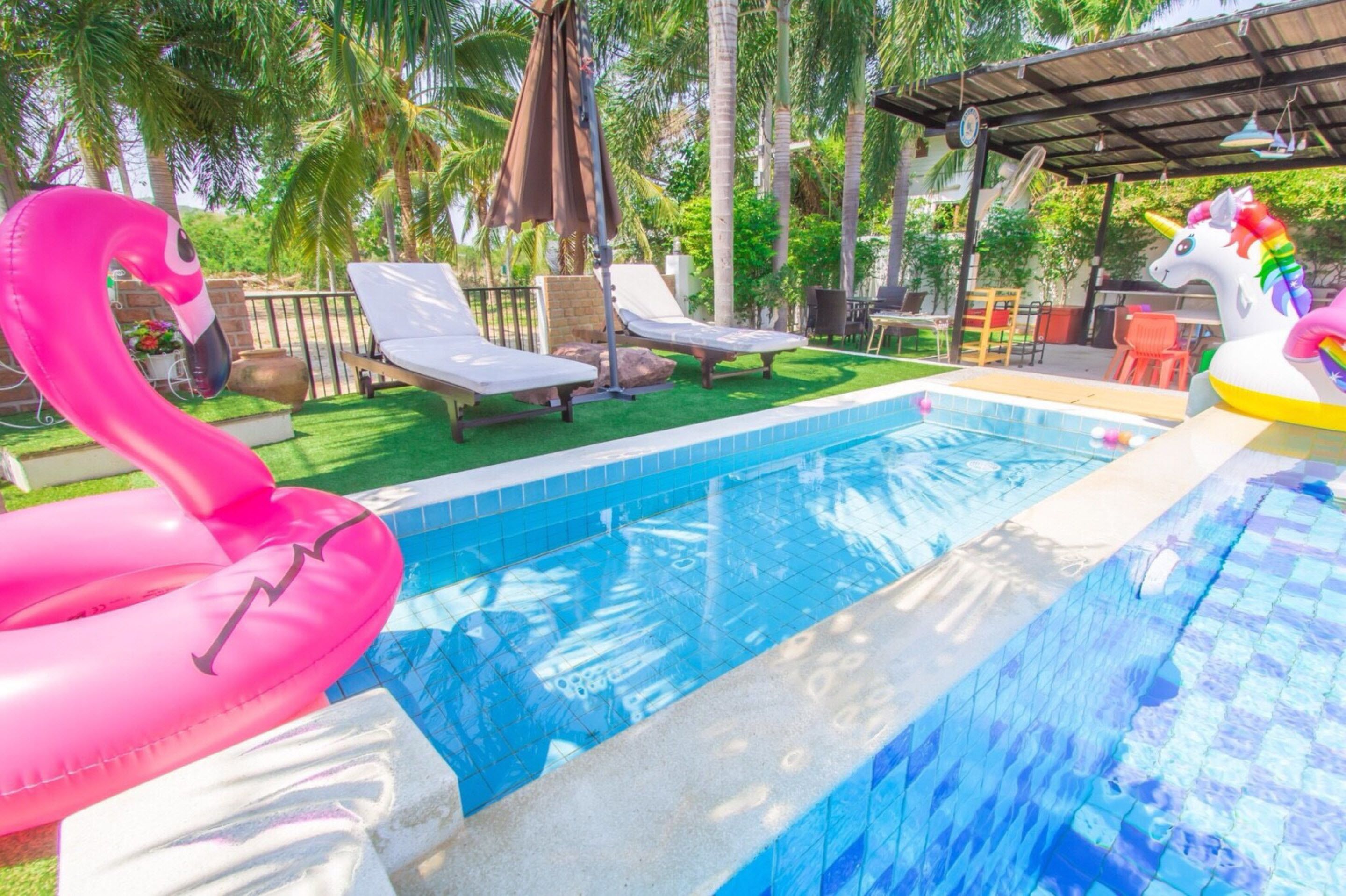 Una piscina con sillas de descanso y juguetes inflables.