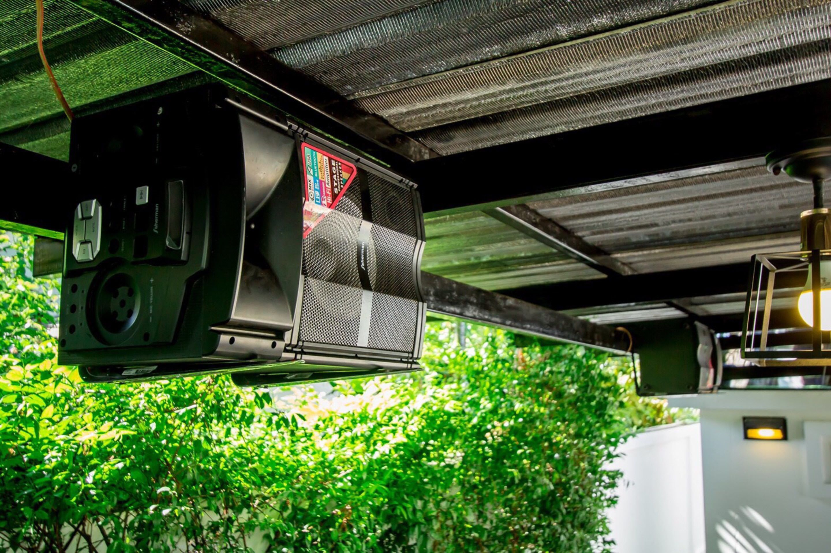 A ceiling-mounted projector with a warning label, a ventilation grille, and a light fixture.