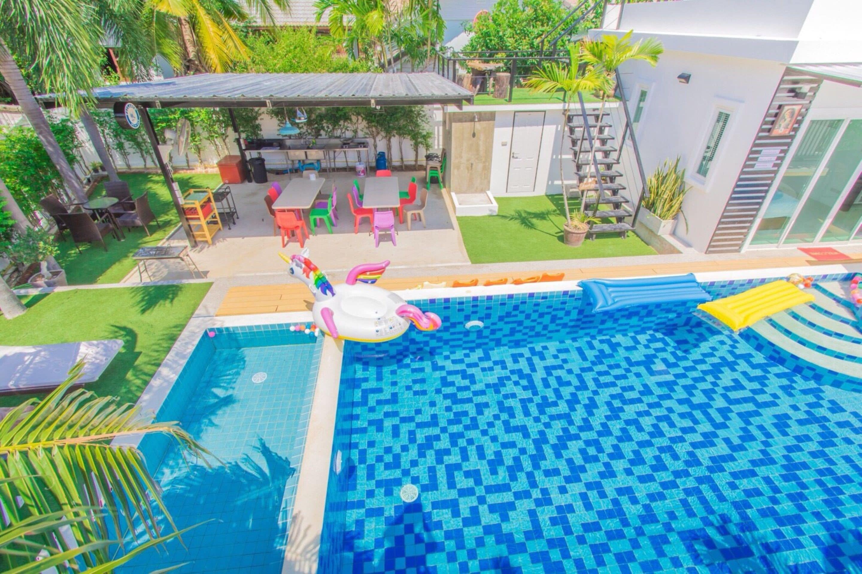 A swimming pool with a colorful inflatable toy, surrounded by a patio area with outdoor furniture and a covered seating area.
