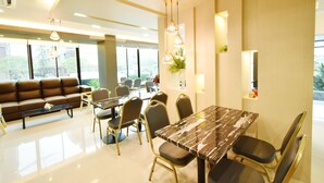 A modern dining area with a marble table, comfortable seating, and pendant lighting. - Grand Inter Hotel (Samut Sakhon)
