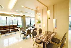 A modern dining area with a marble table, comfortable seating, and pendant lighting.