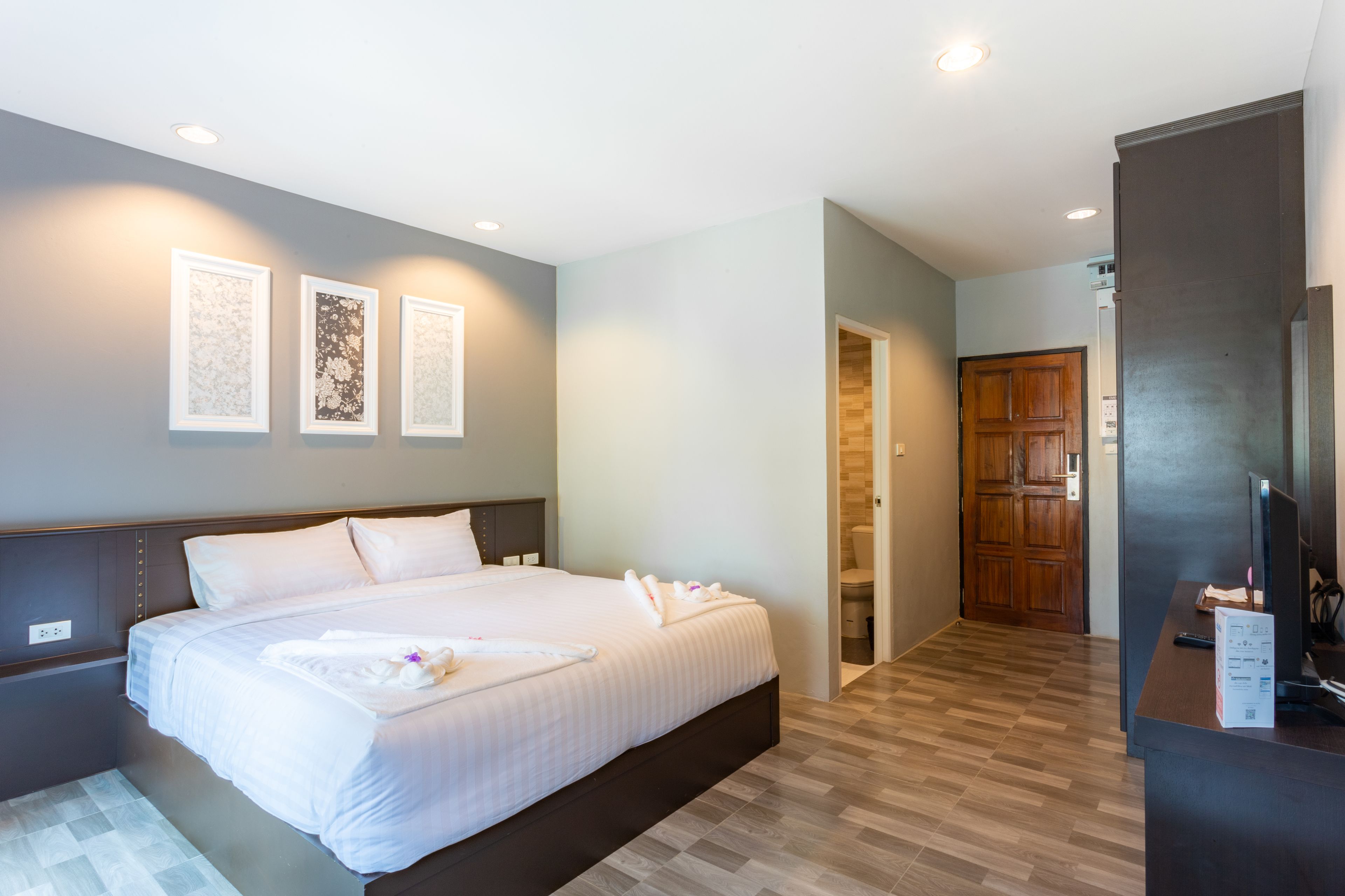 Una habitación de hotel con una cama grande, un escritorio con computadora y una puerta de madera.