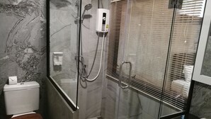 Un baño con ducha envuelta en vidrio, un inodoro y un lavamanos.