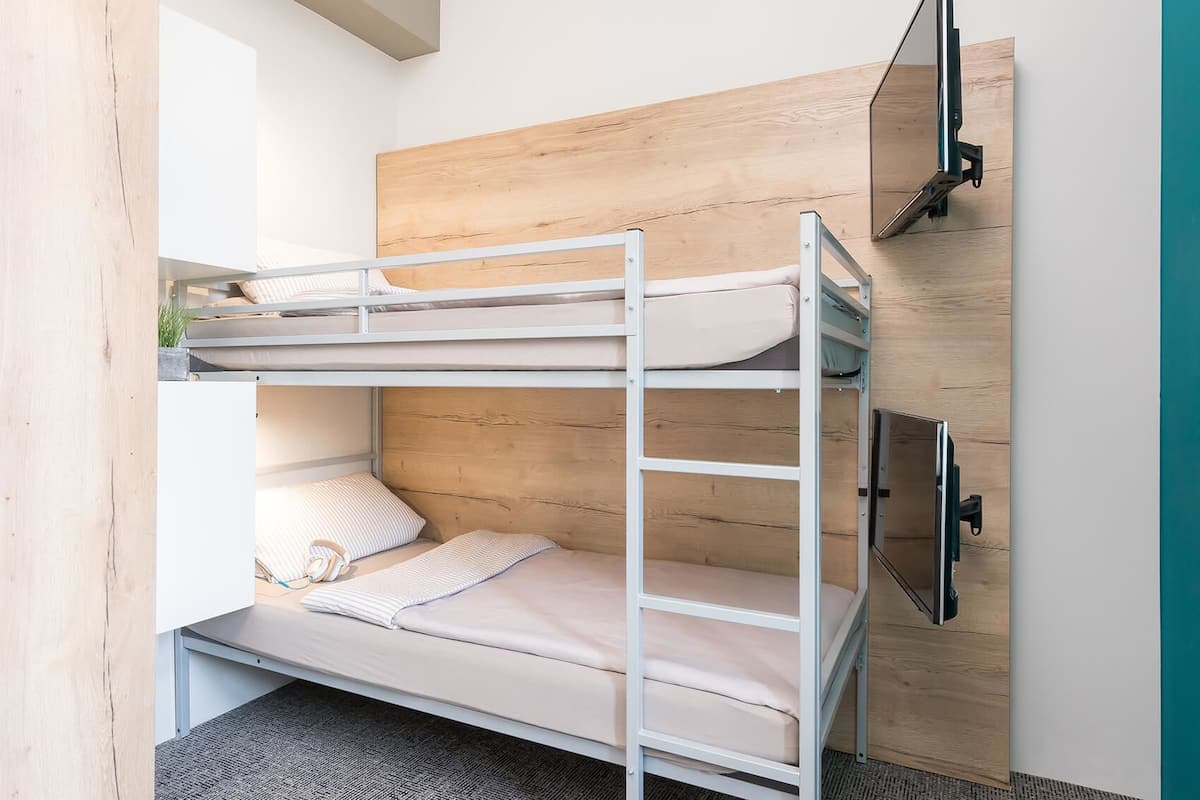 A bunk bed with a TV mounted on the wall above it.