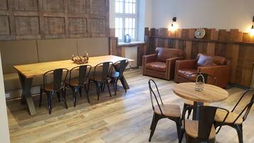 Een moderne woonkamer met een houten eettafel, leren banken en een ronde salontafel.