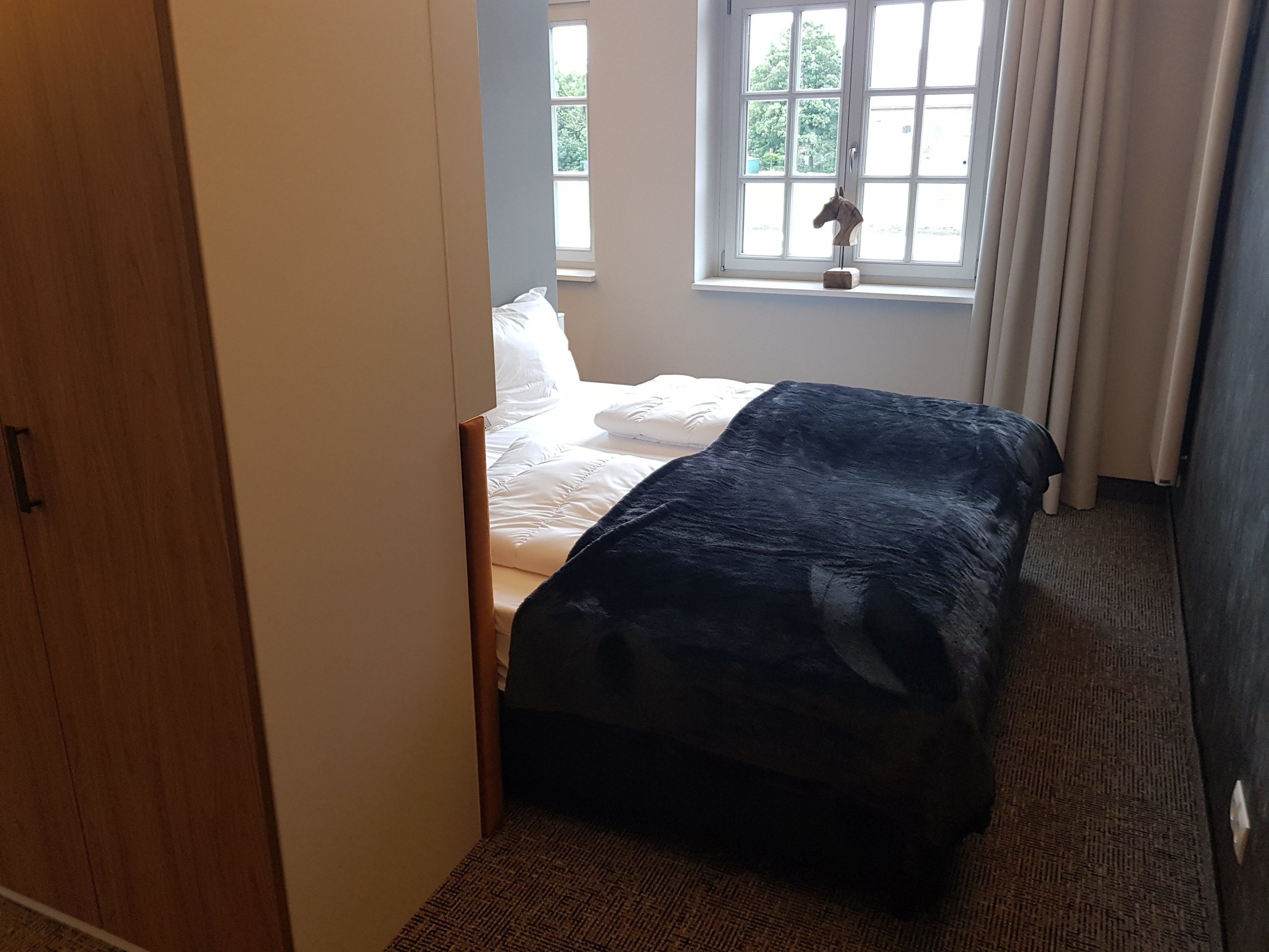 A bedroom with a bed, a window, and a door.