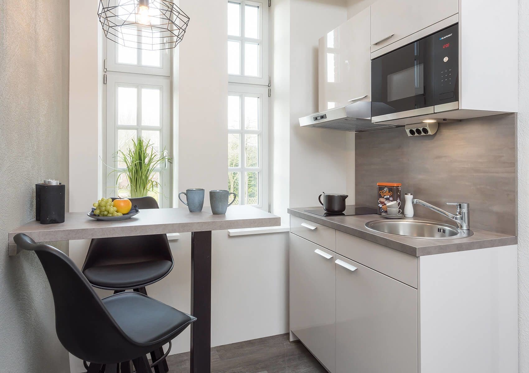 Una cucina moderna con forno a microonde, lavello e zona pranzo con sedie e tavolo.