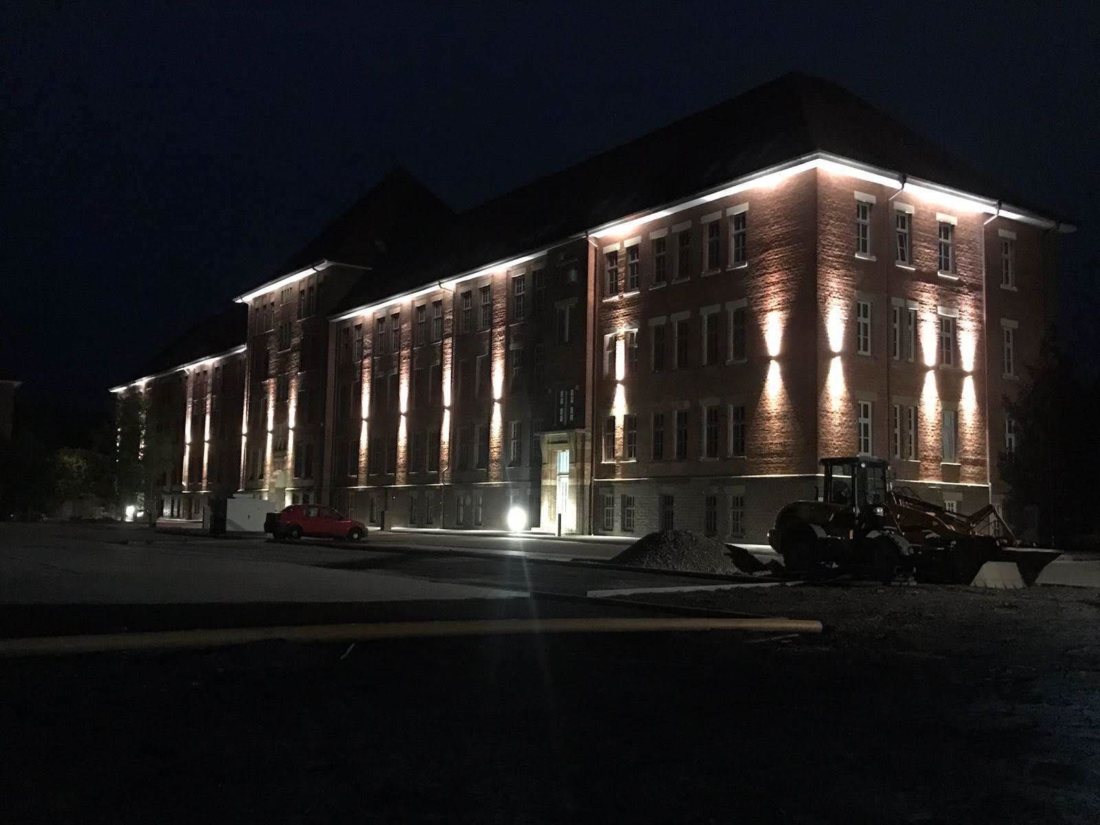A large brick building with multiple windows and a well-lit facade at night.