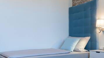 Un dormitorio moderno con cabecera azul, una mesita de noche y una lámpara de pared.