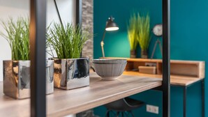 A modern interior with a teal wall, a wooden shelf, and two potted plants.