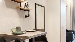 A modern dining area with a minimalist table, chairs, and a wall-mounted shelf with decorative items.