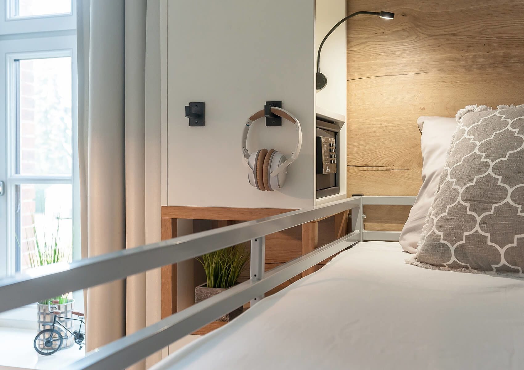 A modern bedroom with a bed, a nightstand, a lamp, and a view of a bicycle outside.