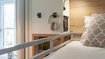 A modern bedroom with a bed, a nightstand, a lamp, and a view of a bicycle outside.